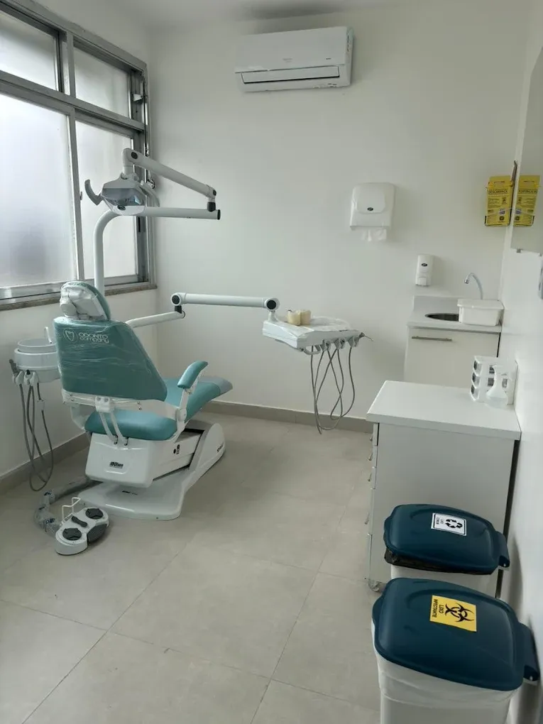 Consultório odontológico com cadeira e descarte de resíduos sinalizado